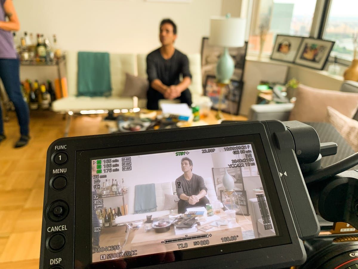 A camera monitor framing an actor on a living-room set